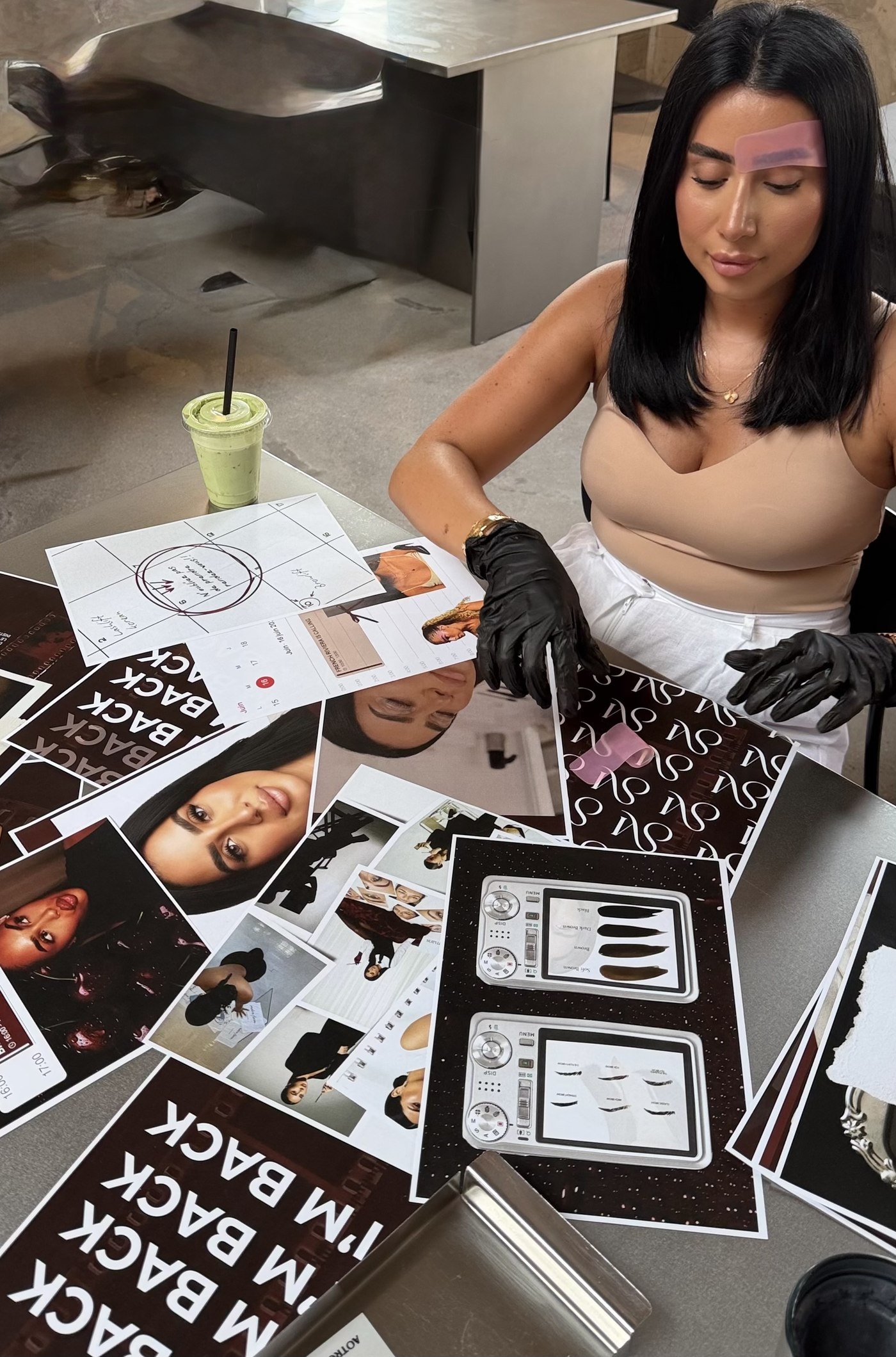 Overhead view of an eyebrow mapping session with mood board photos and camera reference sheets spread across the table