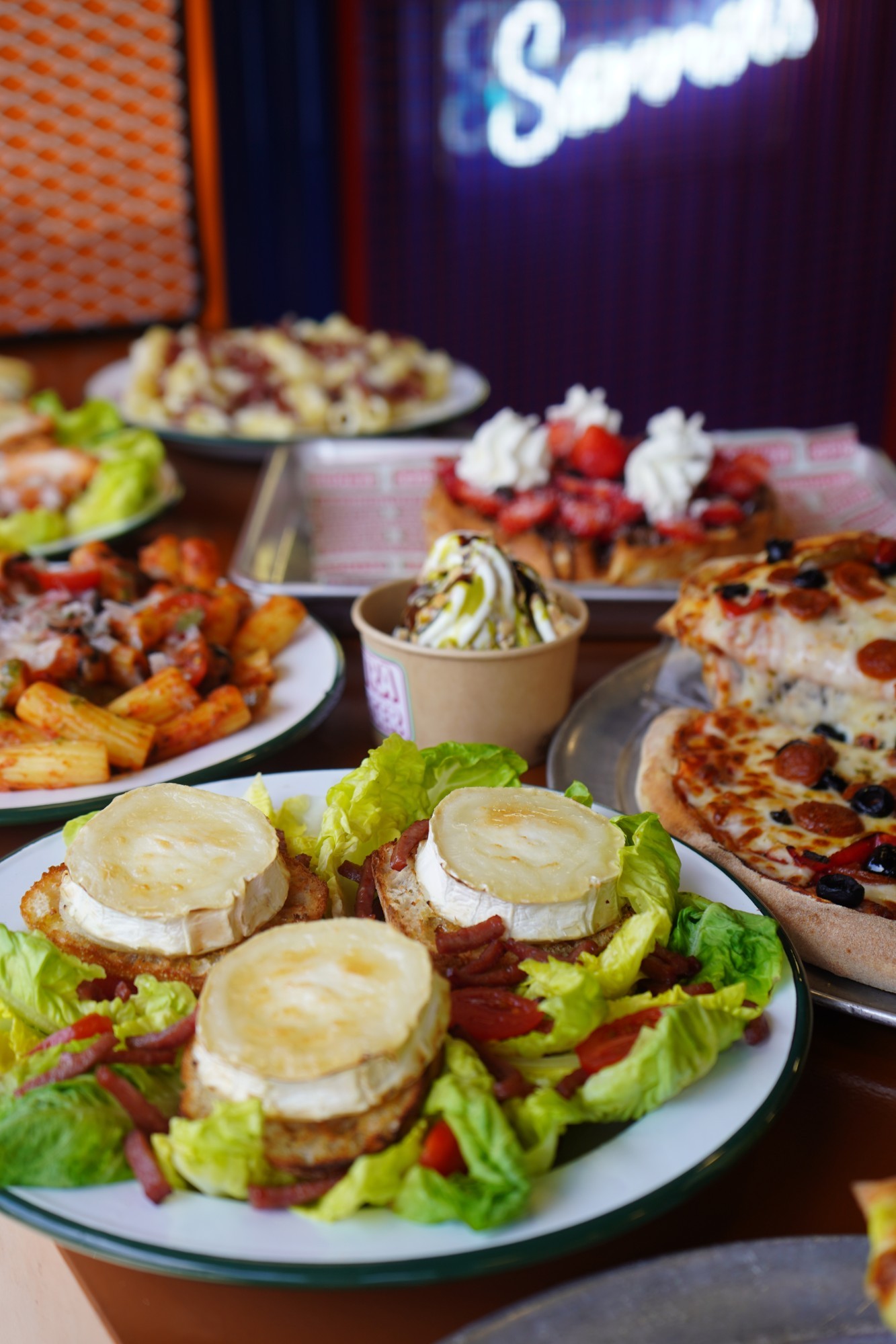 A table spread of warm goat cheese salad, pasta and pizza at Molly Jefferson's