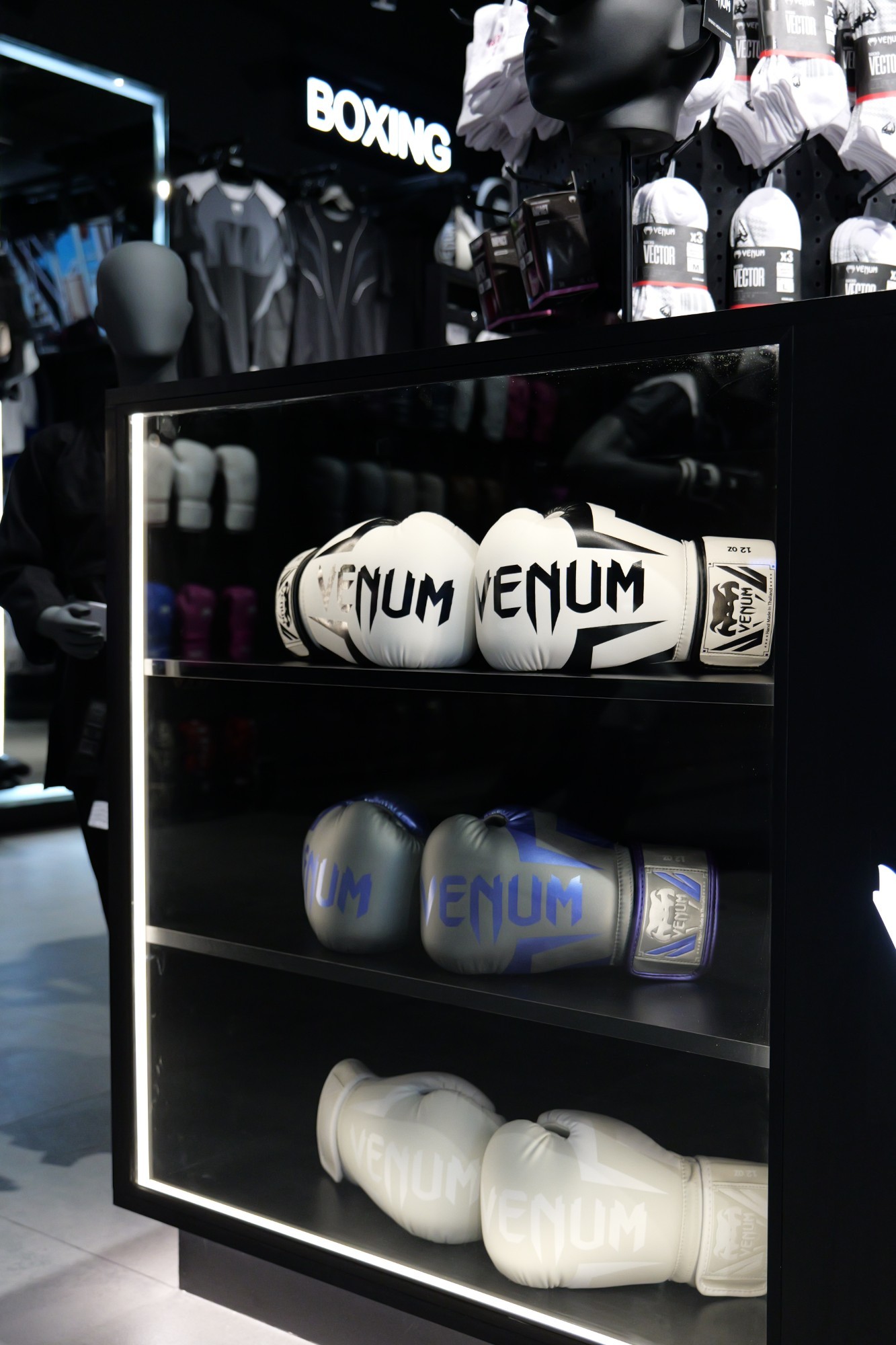 Venum boxing gloves displayed in a glass case at a My Fight House retail store